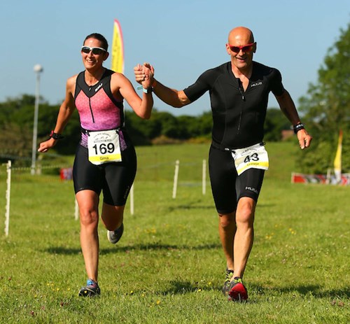 Two athletes running while linking hands.